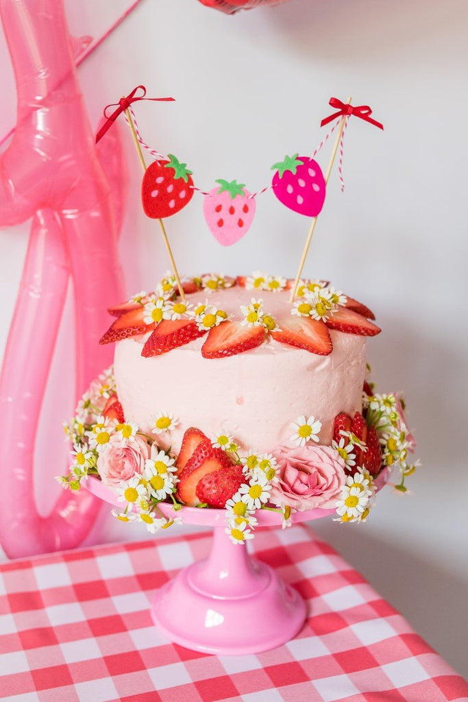 pink cake stand with strawberry cake banner